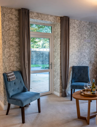 Inside the show home lounge area with chairs, coffee table and bright lighting 