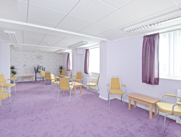 Communal room with purple carpet and curtains with music system, seating and tables