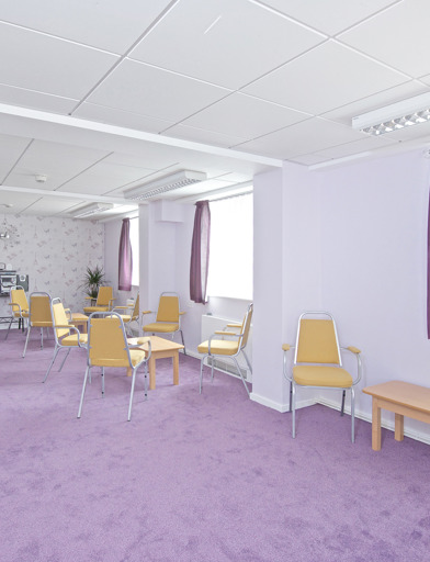 Communal room with purple carpet and curtains with music system, seating and tables