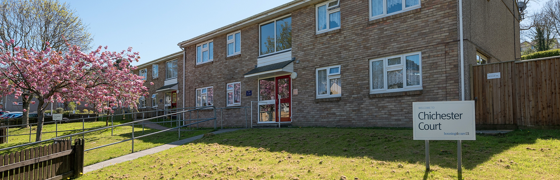 A path with handrail leading up to the main front door of the scheme with grassed areas either side