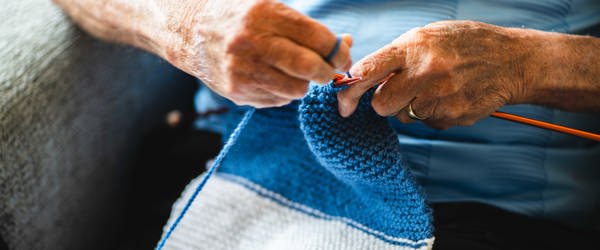 A man in a football shirt knits a scarf