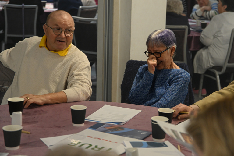 Two residents trying to control their laughter while sat at a table
