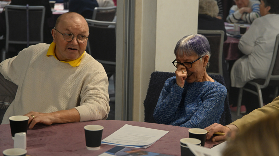 Two residents trying to control their laughter while sat at a table