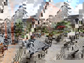 Hard-landscaped garden area with tables, seating, and plants and flowers