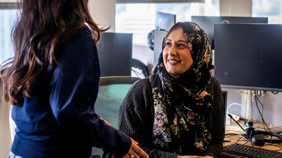 Two women speak at a computer