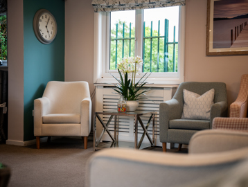 Three comfy cream chairs in the corner of the communal lounge