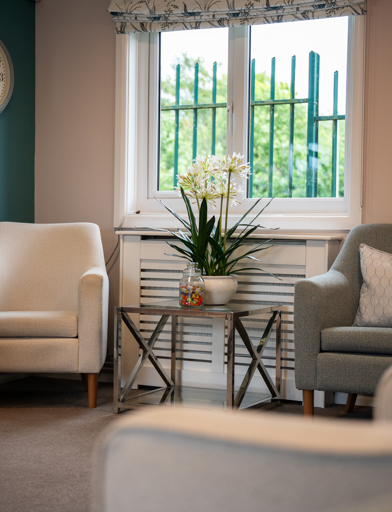 Three comfy cream chairs in the corner of the communal lounge 
