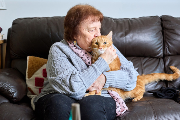 A resident cuddles her cat on the sofa