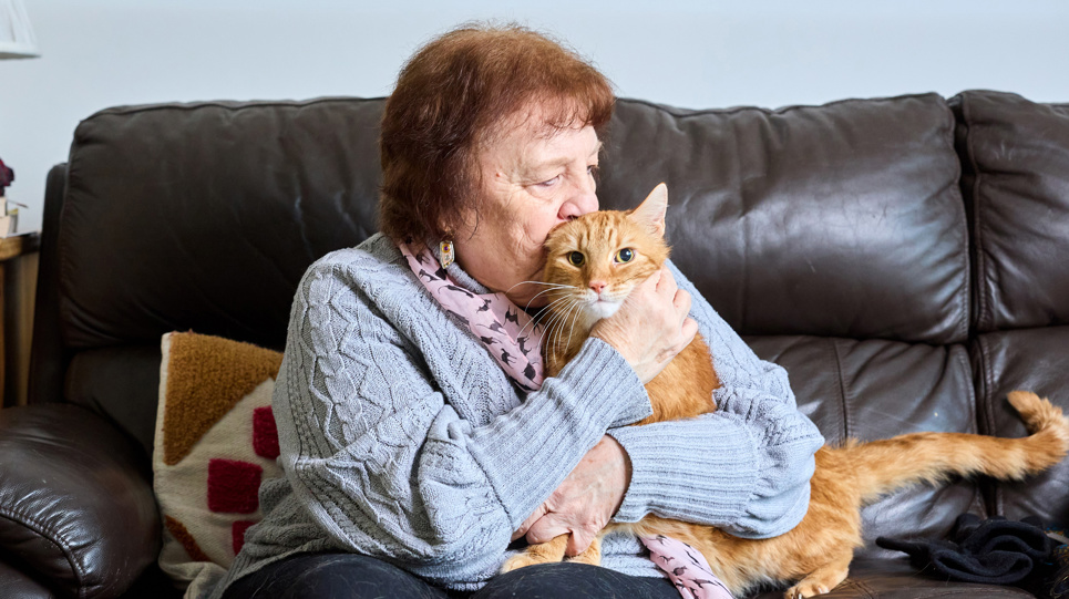 A resident cuddles her cat on the sofa