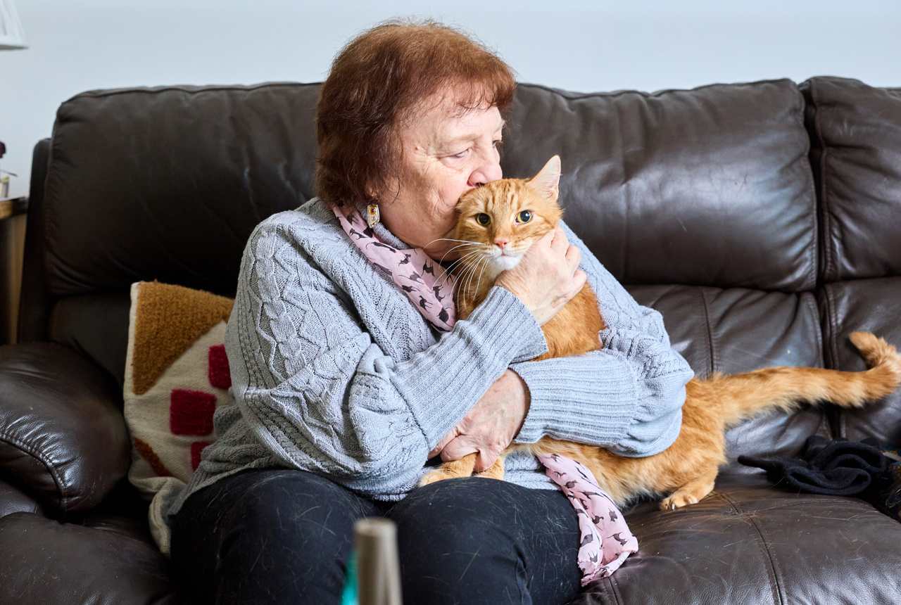 A resident cuddles her cat on the sofa