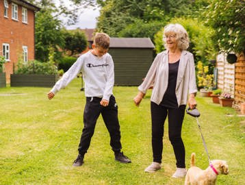 Resident with a young family member and a dog outside 