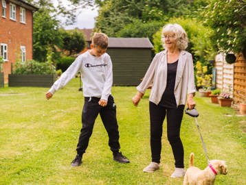 Resident with a young family member and a dog outside 