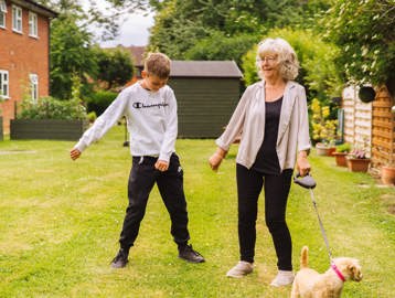 Resident with a young family member and a dog outside 