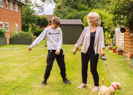 Resident with a family member and a dog outside 