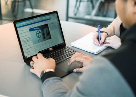 A Housing 21 employee works on a laptop which is displaying policy information