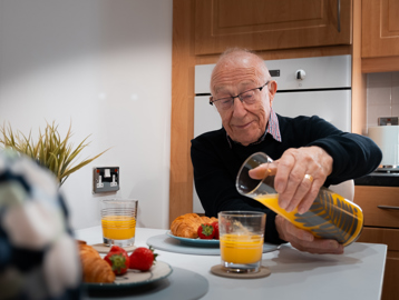 A resident enjoying breakfast with his friend in their apartment