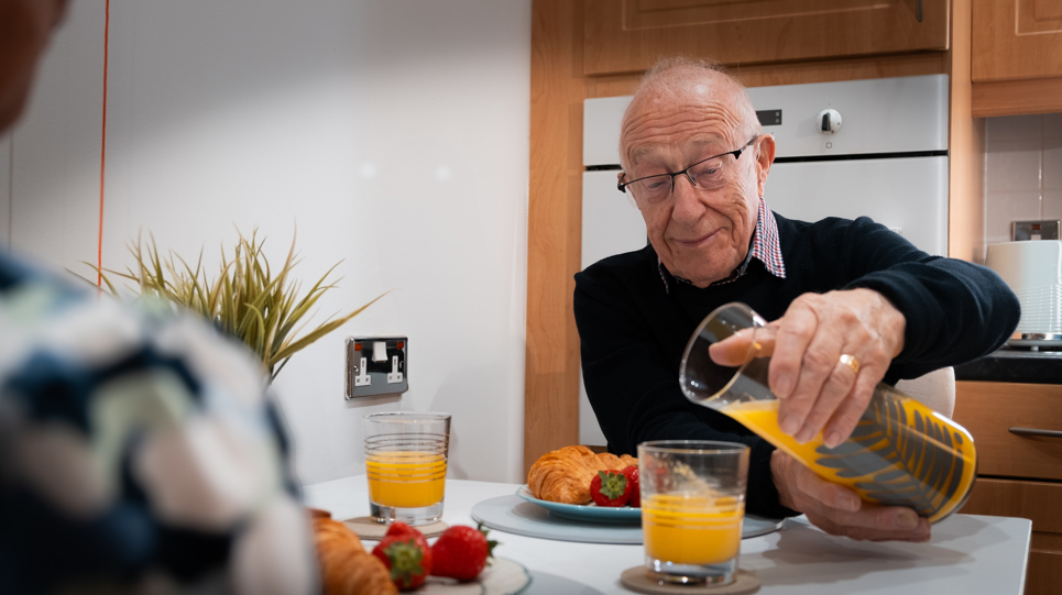 A resident enjoying breakfast with his friend in their apartment