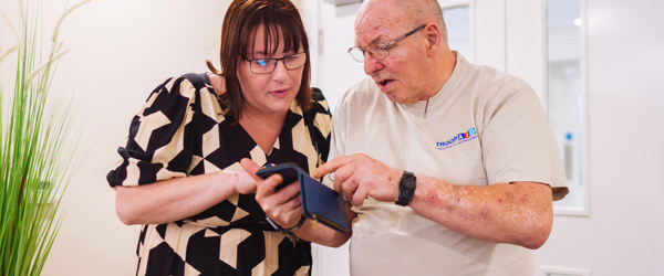 An employee helping a Retirement Living resident to find something on their mobile phone