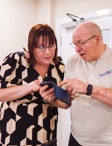An employee helping a Retirement Living resident to find something on their mobile phone 