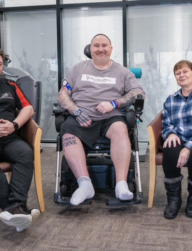 Chris, a Housing 21 resident, sits in the middle of his sister Wendy (to his left) and his physio Marc, who sits to his right 