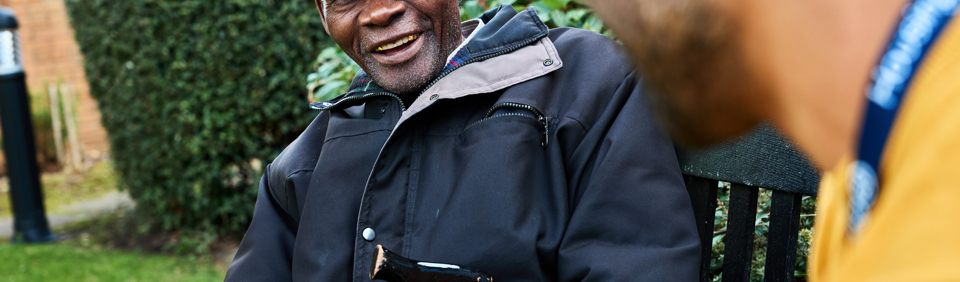 Resident smiling in the garden sat on a bench 