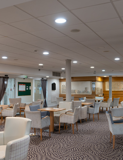 The cafe/bistro with ample seating, tables and a bar with dart board 