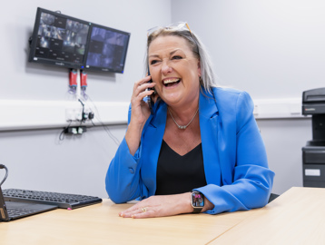 A Housing 21 employee laughing as she talks on a mobile phone