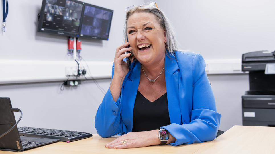 A Housing 21 employee laughing as she talks on a mobile phone