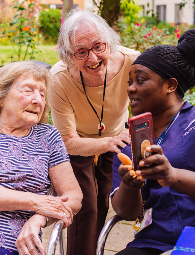 Residents and a Care Worker looking at a mobile phone 