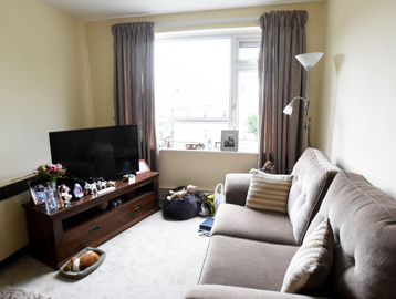 Inside the living room of a resident's apartment with sofa, TV and ornaments