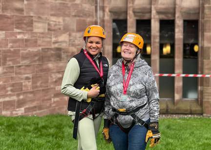 A Housing 21 employee and resident outside Coventry Cathedral in harnesses and hard hats.