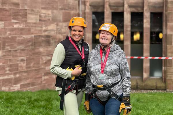 A Housing 21 employee and resident outside Coventry Cathedral in harnesses and hard hats.