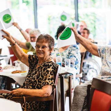 Residents at a conference holding up pieces of paper with green smiley faces on them