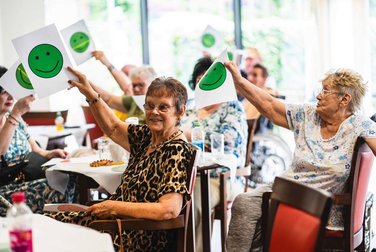 Residents at a conference holding up pieces of paper with green smiley faces on them