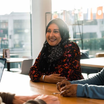 A woman smiles talking to colleagues