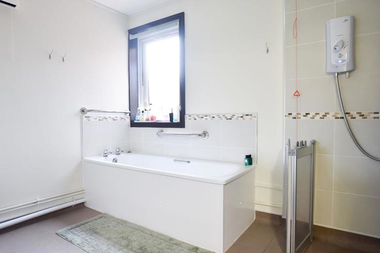 An assisted bathroom with bath and walk-in shower at Alan Hilton Court