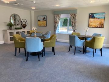 Blue and green chairs placed around round tables in a communal space at Michaelmas Court 