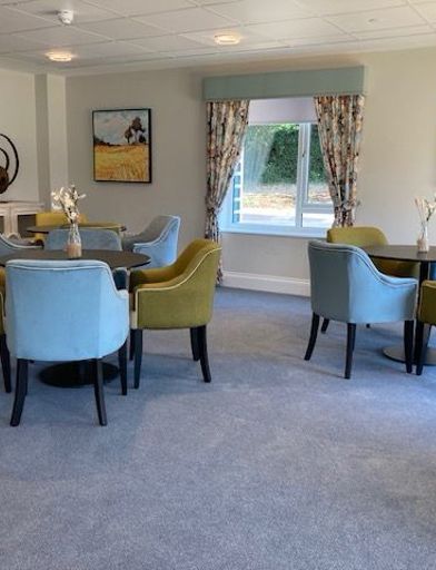 Blue and green chairs placed around round tables in a communal space at Michaelmas Court  