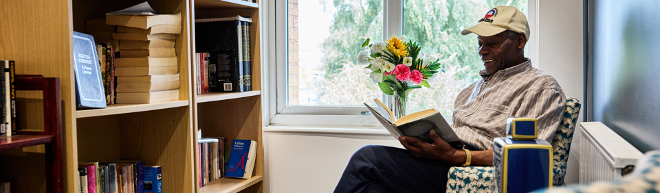 Resident sitting down reading a book 