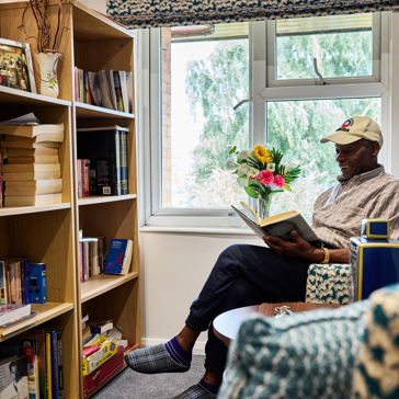 Resident sitting down reading a book