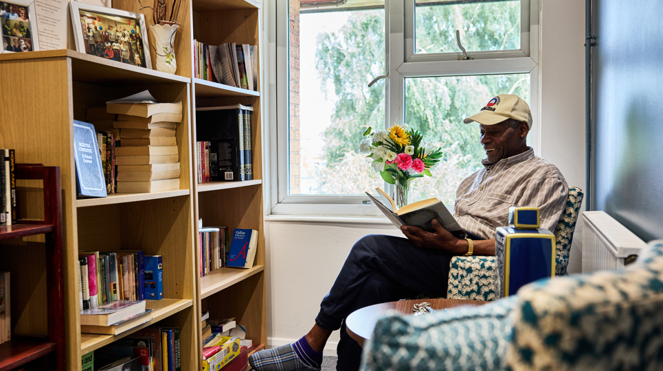 Resident sitting down reading a book