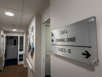 William Griffiths Court internal shot: Hallway with a sign pointing to flats and the communal lounge