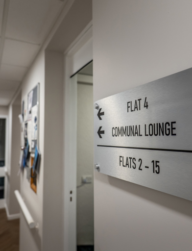 William Griffiths Court internal shot: Hallway with a sign pointing to flats and the communal lounge 