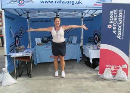 Housing 21 employee Hazel standing in a Royal Air Force Association tent with arms wide 