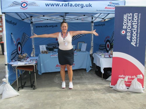 Housing 21 employee Hazel standing in a Royal Air Force Association tent with arms wide