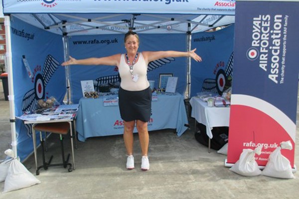 Housing 21 employee Hazel standing in a Royal Air Force Association tent with arms wide 