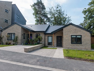 An image showing the outside of a bungalow at Bowland View. The bungalow features a patio with a small grassed area