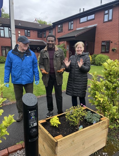 Two residents and the local manager who have been gardening in a cloudy Manchester 