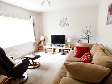 Living room in a residents' lounge with sofa, armchair and TV on a small unit