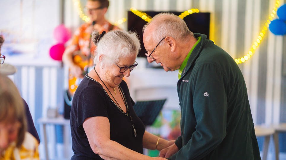 A couple facing each other and holding hands whilst dancing 